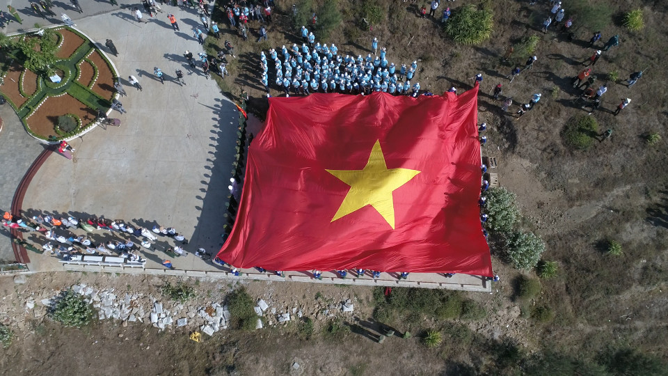 Sau lễ thượng cờ, lá quốc kỳ rộng 250 mét vuông được căng rộng trên triền núi, phủ kín khu vực làm lễ chào cờ. (Ảnh: Lâm Phan/Vietnam+)