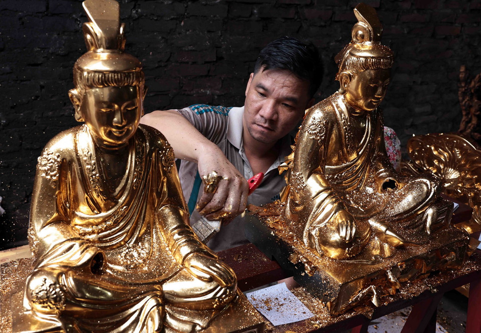 Tượng phật được thếp vàng qua bàn tay khéo léo của người thợ Sơn Đồng. (Ảnh: Trần Việt/TTXVN)