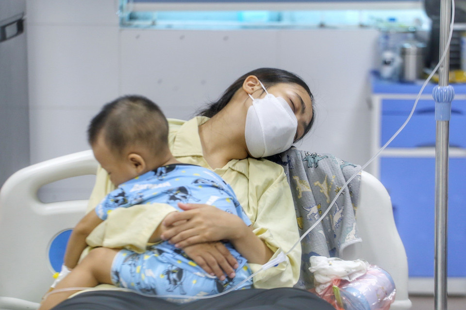 Người mẹ ngủ thiếp khi điều trị cho con tại bệnh viện. (Ảnh: Tuấn Đức/TTXVN)