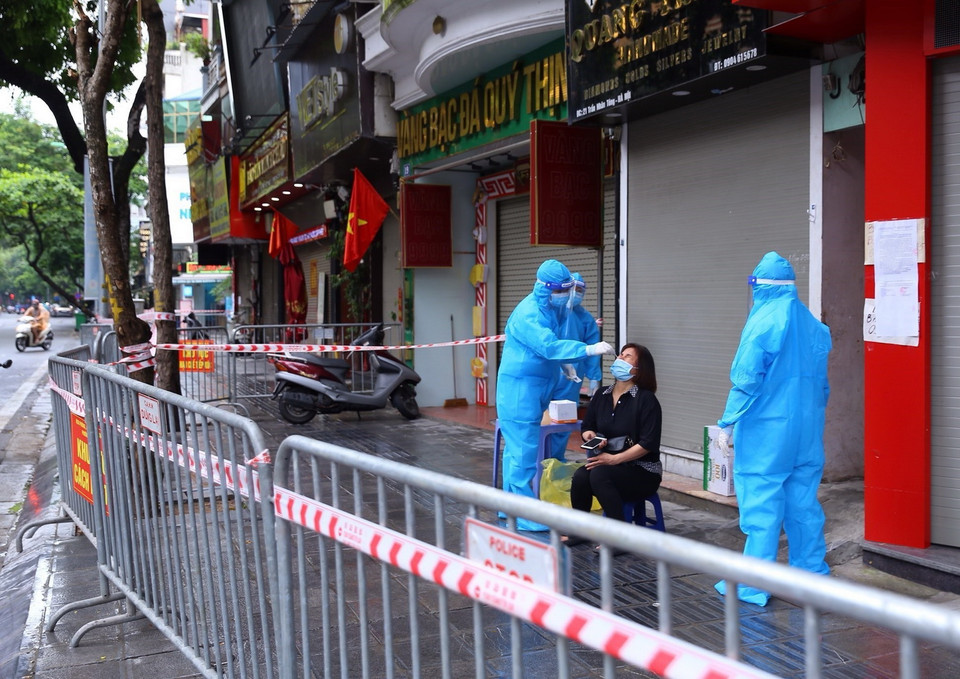 Người dân trong ngõ 21 Trần Nhân Tông được nhân viên y tế lấy mẫu xét nghiệm. (Ảnh: Hoàng Hiếu/TTXVN) 