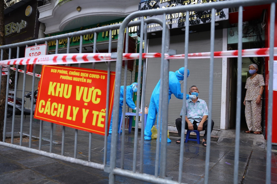 Lực lượng y tế phường Nguyễn Du lấy mẫu xét nghiệm cho người dân trong ngõ 21 Trần Nhân Tông. (Ảnh: Hoàng Hiếu/TTXVN) 