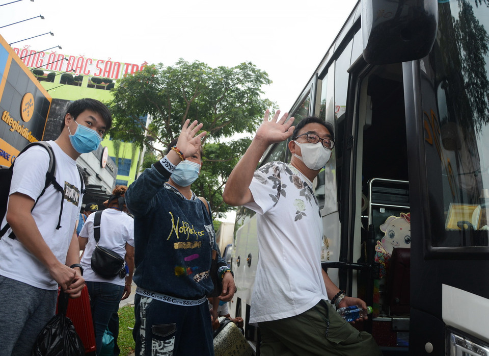 Du khách hoàn thành cách ly chào tạm biệt, lên xe ra sân bay trở về nước. (Ảnh: Văn Dũng/TTXVN)