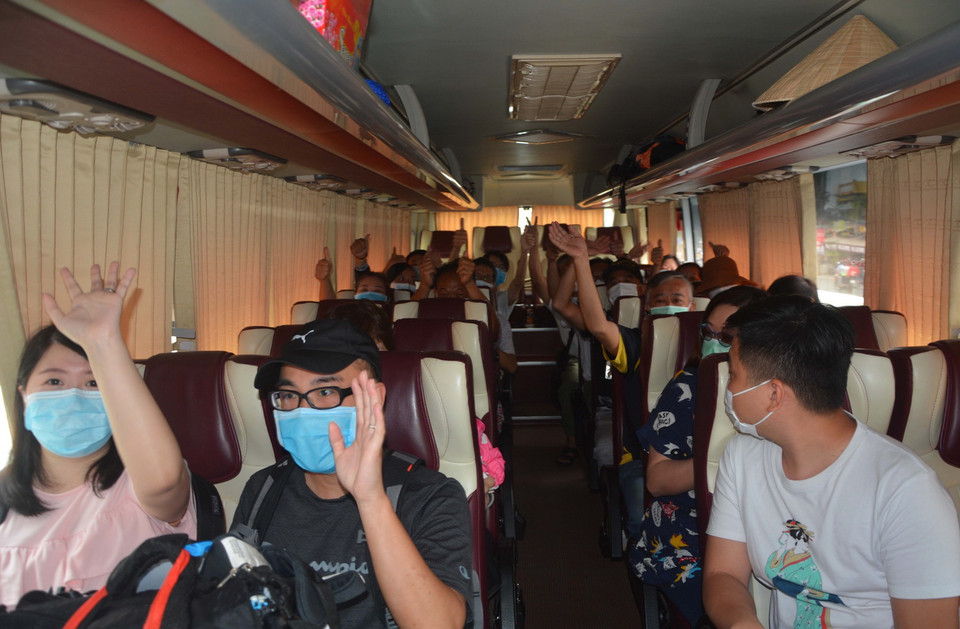 Du khách hoàn thành cách ly chào tạm biệt, lên xe ra sân bay trở về nước. (Ảnh: Văn Dũng/TTXVN)