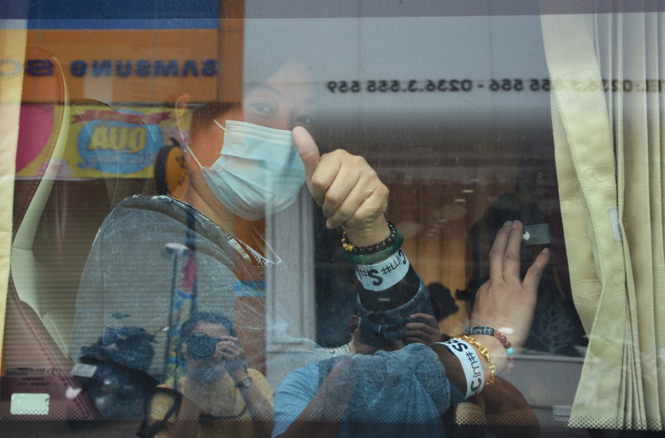 Du khách hoàn thành cách ly chào tạm biệt, lên xe ra sân bay trở về nước. (Ảnh: Văn Dũng/TTXVN)