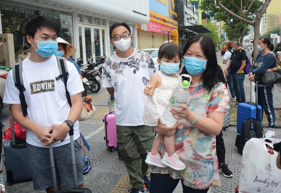 Du khách hoàn thành cách ly đứng chờ xe chuyên biệt đưa ra sân bay. (Ảnh: Văn Dũng/TTXVN)