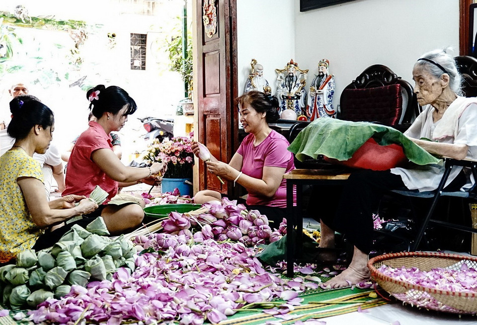 Nghệ nhân Nguyễn Thị Dần (101 tuổi) cùng các thành viên trong gia đình thực hiện các công đoạn ướp trà sen truyền thống. (Ảnh: Khánh Hòa/TTXVN)