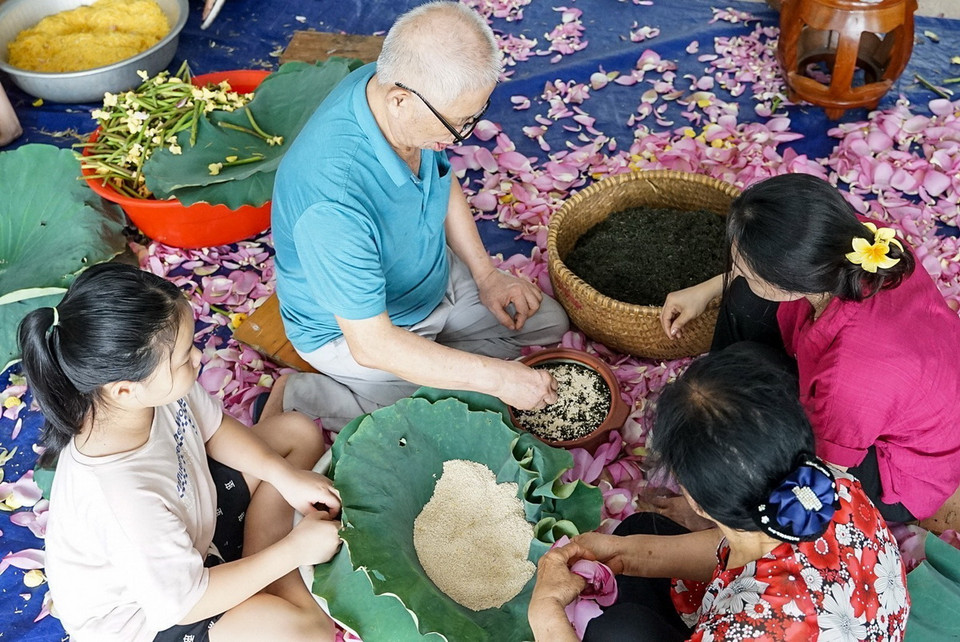 Ướp trà là công đoạn “then chốt” của nghề ướp sen truyền thống Tây Hồ, thường thì sẽ do người nghệ nhân chính đảm nhiệm, các thành viên trong gia đình sẽ quan sát, và học nghề. (Ảnh: Khánh Hòa/TTXVN)