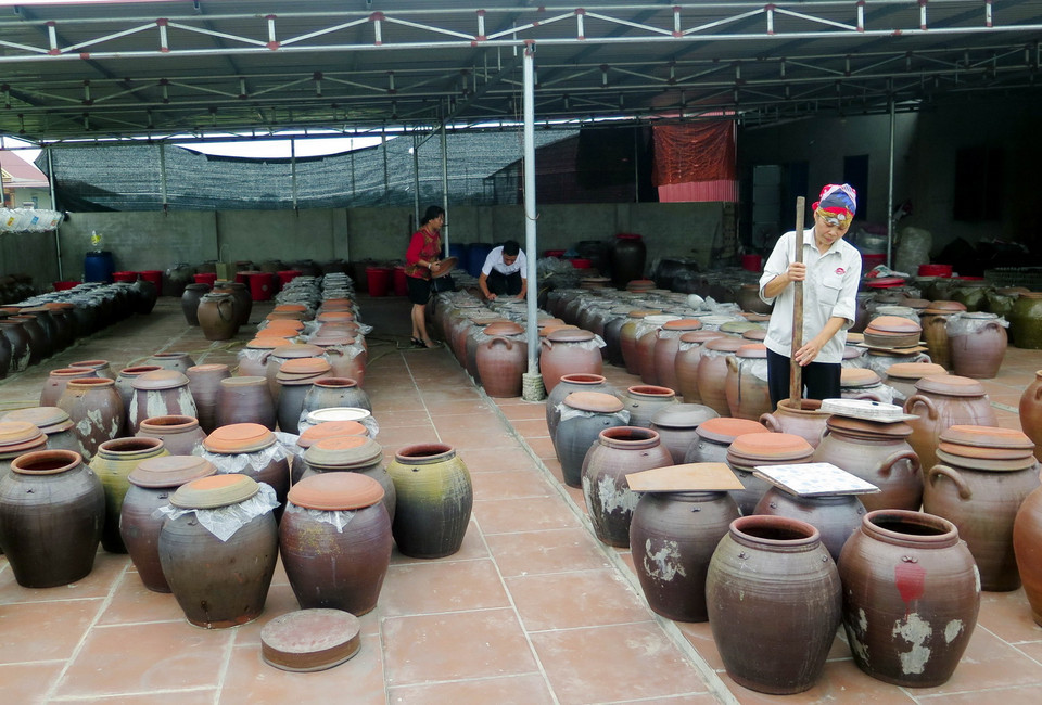 Người dân sử dụng chum sành để ngả tương và sử dụng gậy tre sạch để khuấy đều 2-3 lần/ngày. (Ảnh: Quân Trang/TTXVN)