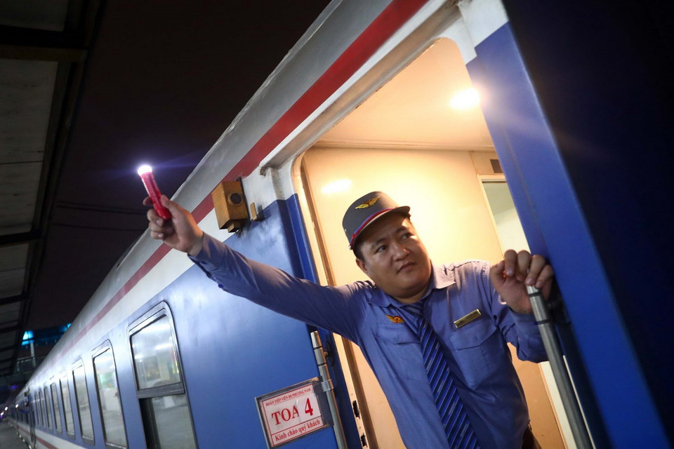 Nhân viên đường sắt ra hiệu lệnh tàu bắt đầu lăn bánh. (Ảnh: Huy Hùng/TTXVN)