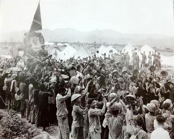 Lá cờ “Quyết chiến Quyết thắng” và chân dung Chủ tịch Hồ Chí Minh tại lễ diễu hành mừng chiến thắng tại Điện Biên Phủ giữa tiếng reo hò vang dậy của bộ đội, dân công và nhân dân các dân tộc Điện Biên. (Ảnh: Tư liệu TTXVN phát)