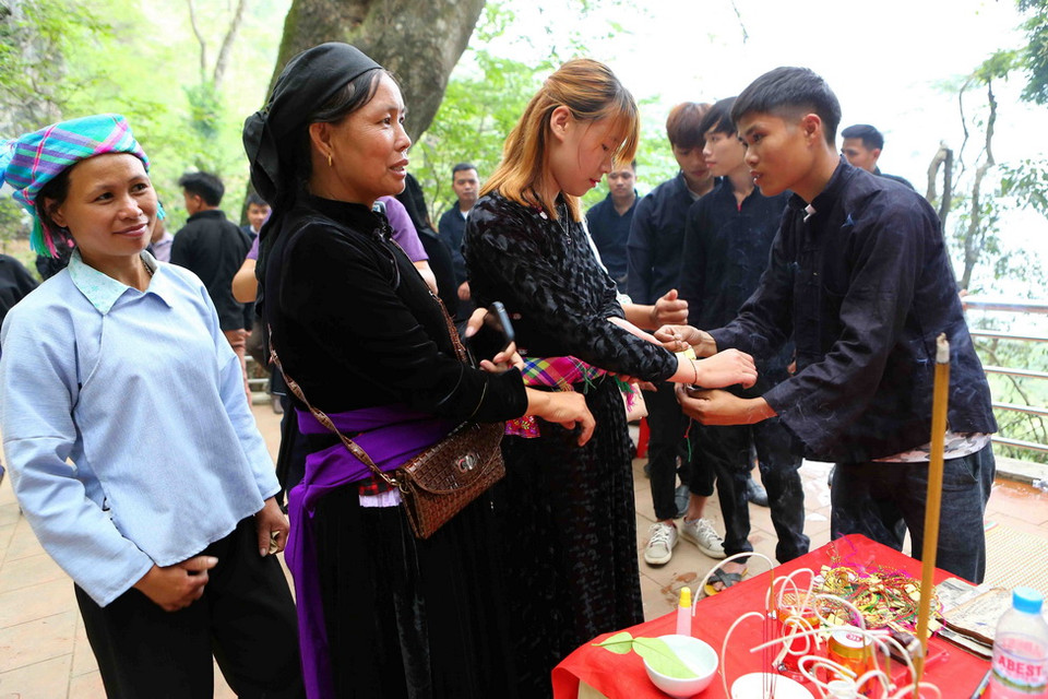  Nghi lễ đeo bùa tay may mắn tại lễ dâng hương Miếu Ông, Miếu Bà. (Ảnh: Thành Đạt/TTXVN)