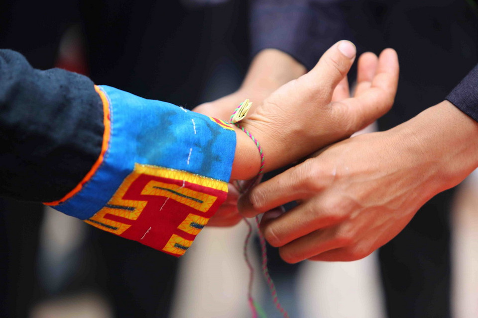  Nghi lễ đeo bùa tay may mắn tại lễ dâng hương Miếu Ông, Miếu Bà. (Ảnh: Thành Đạt/TTXVN)