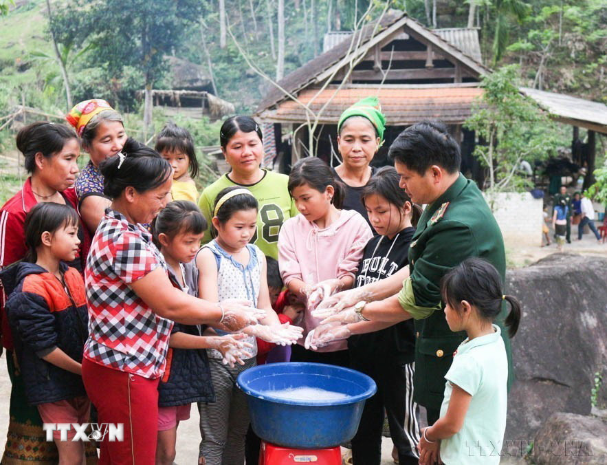 Bộ đội biên phòng đồn Hạnh Dịch, huyện Quế Phong, tỉnh Nghệ An, hướng dẫn bà con cách rửa tay đúng cách để phòng dịch COVID-19. (Ảnh: Nguyễn Oanh/TTXVN)