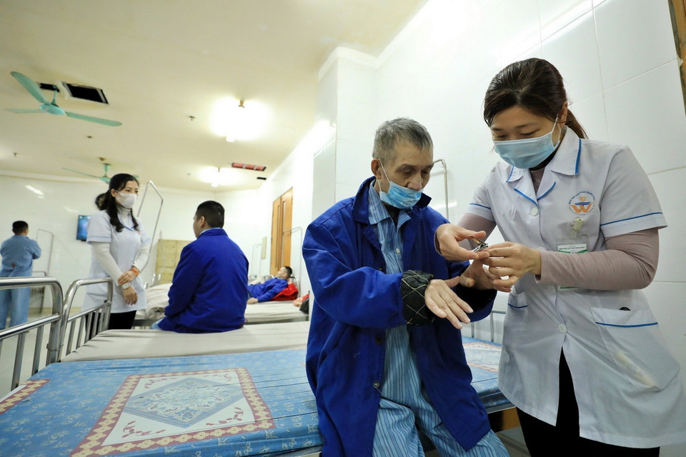 Các y bác sỹ cắt móng tay cho người bệnh. (Ảnh: Minh Quyết/TTXVN)