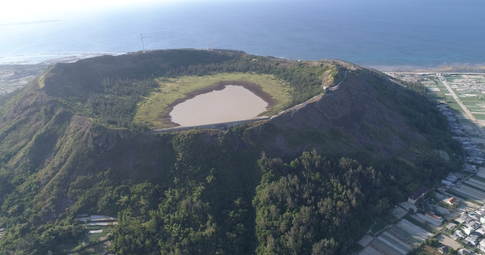Từ trên cao nhìn xuống, miệng núi lửa Giếng Tiền hệt như 'chiếc chảo khổng lồ' nhô lên giữa biển trời huyện đảo Lý Sơn. Miệng núi lửa này rộng hàng trăm mét, cao 30-40 mét nghiêng về phía bắc, có niên đại khoảng 1 triệu năm. (Ảnh: Tùng Lâm/Vietnam+)