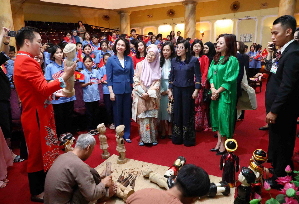 Phu nhân Thủ tướng Việt Nam Lê Thị Bích Trân và Phu nhân Thủ tướng Malaysia Dato' Seri Dr. Wan Azizah binti Dr. Wan Ismail nghe giới thiệu công việc tạo hình quân rối nước của các nghệ nhân. (Ảnh: Phạm Kiên/TTXVN)
