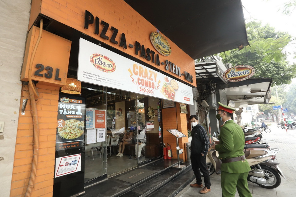  Lực lượng chức năng phường Tràng Tiền (quận Hoàn Kiếm) nhắc nhở các hộ kinh doanh thực hiện theo quy định của quận. (Ảnh: Minh Quyết/TTXVN)