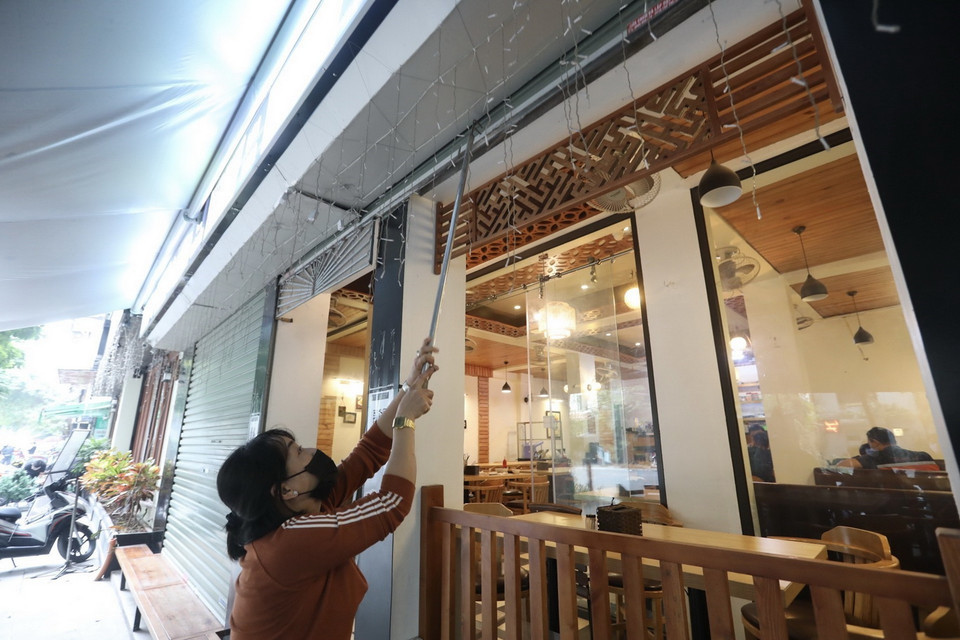  Cửa hàng trên địa bàn phường Phan Chu Trinh, quận Hoàn Kiếm thực hiện đóng cửa, chỉ bán hàng mang về từ trưa 26/12/2021. (Ảnh: Minh Quyết/TTXVN)