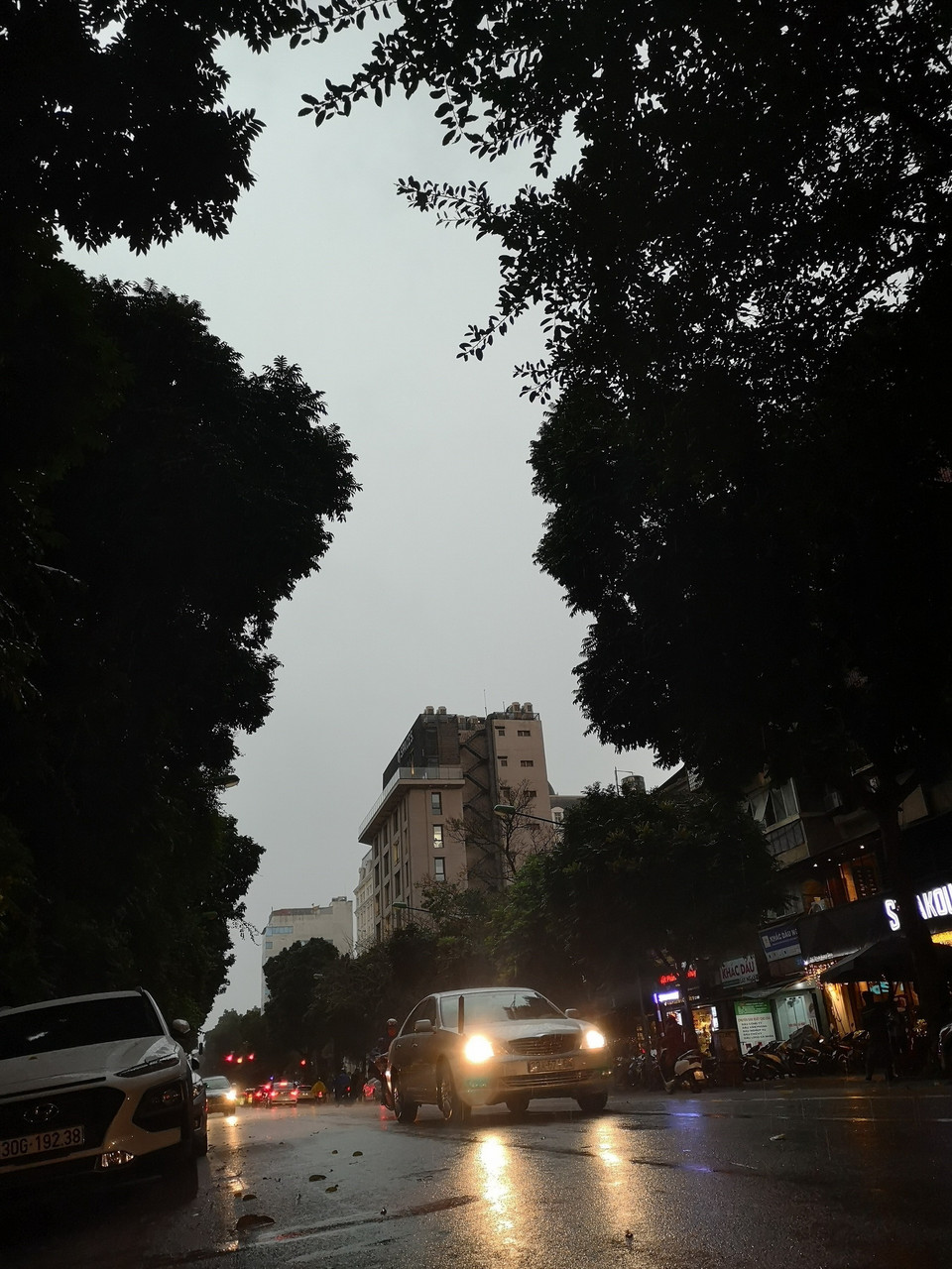 Bầu trời Hà Nội tối sầm, kèm mưa lớn khiến các phương tiện giao thông phải bật đèn khi di chuyển. (Ảnh: Thanh Tùng/TTXVN)