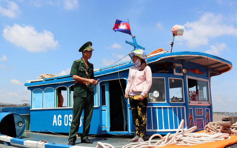 Chiến sỹ Đồn Biên phòng cửa khẩu quốc tế Thường Phước, tỉnh Đồng Tháp kiểm tra giấy tờ thuyền viên trên tàu nhập cảnh vào Việt Nam. (Ảnh: Xuân Khu/TTXVN)