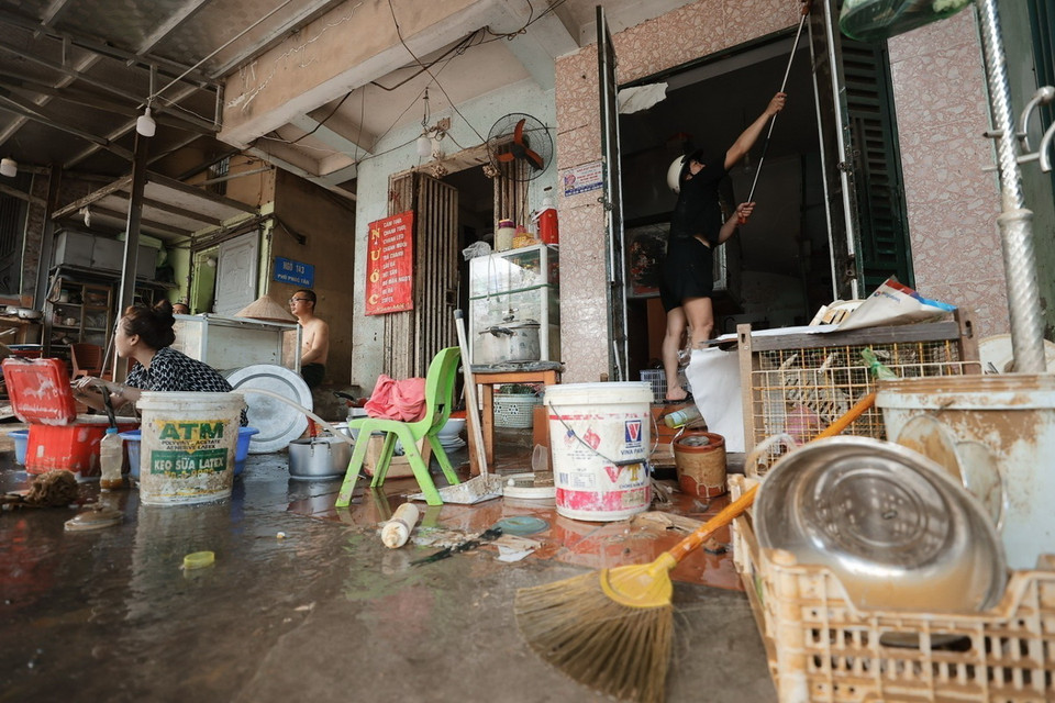 Người dân phường Phúc Tân, quận Hoàn Kiếm dọn dẹp vệ sinh nhà cửa sau khi nước rút (ảnh chụp lúc 10 giờ 5 phút). (Ảnh: Minh Quyết/TTXVN)