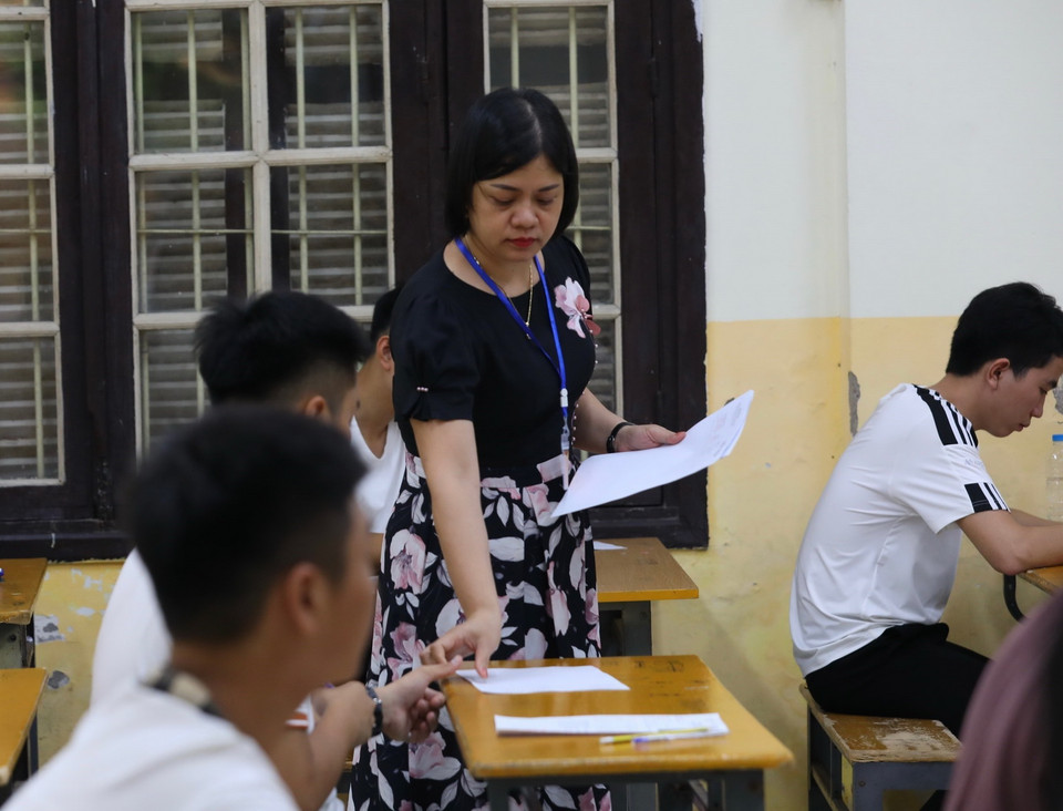 Giám thị phát giấy nháp cho thí sinh điểm thi Trường THPT Phan Đình Phùng, quận Ba Đình, Hà Nội. (Ảnh: Hoàng Hiếu/TTXVN)