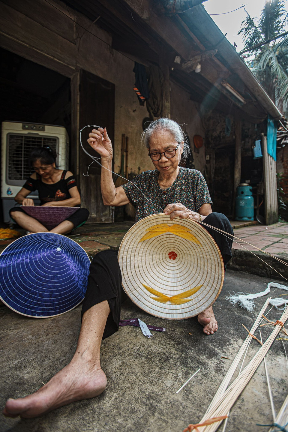 Người thợ dùng vòng liếc, vòng kèm, cước đỏ, kim để làm công đoạn cuối cùng làm nên chiếc nón, được gọi là "nức nón." (Ảnh: Phạm Tuấn Anh/TTXVN)