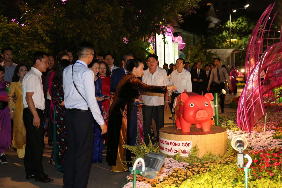 Chủ tịch Quốc hội Nguyễn Thị Kim Ngân bỏ ống nuôi heo đất Tết làm điều hay, chung tay đóng góp cho học sinh nghèo Thành phố Hồ Chí Minh tại Đường hoa Tết Kỷ Hợi 2019. (Ảnh: Thanh Vũ/TTXVN)