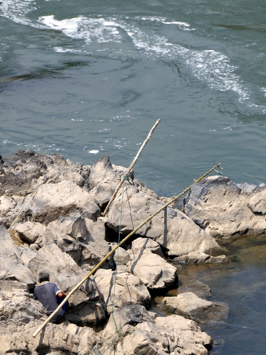 Một người dân địa phương đang câu cá ở đoạn chân thác. (Ảnh: Phạm Kiên/Vietnam+)