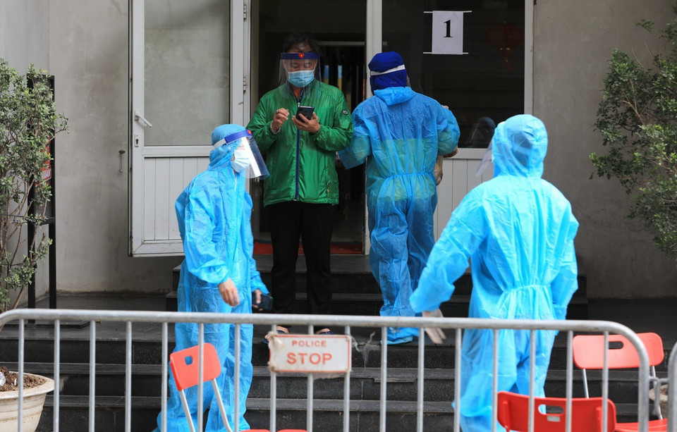 Lối lên của tòa nhà N03 được bố trí nhân viên chức năng trang bị áo bảo hộ kiểm soát việc ra vào và tiếp nhận đồ từ bên ngoài. (Ảnh: Thành Đạt/TTXVN)