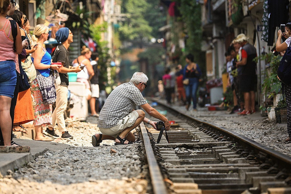 Một nhiếp ảnh gia đặt máy ảnh ở vị trí trên đường ray để ghi lại một khoảnh khắc đẹp khi đoàn tàu đến. (Ảnh: Trọng Đạt/TTXVN)