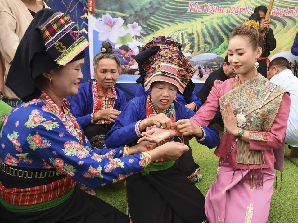 Nghi thức buộc chỉ cổ tay cầu may, chúc phúc cho người được buộc chỉ một năm mới bình an, không ốm đau bệnh tật. (Ảnh: Xuân Tư/TTXVN)