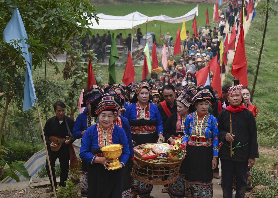  Đoàn người do bà mo dẫn đầu đi xin nước các gia đình trong bản với ý nghĩa cầu may. (Ảnh: Xuân Tư/TTXVN)