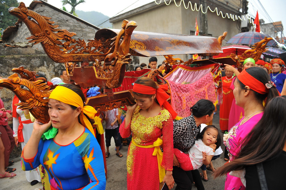 Một người phụ nữ bế con chạy qua kiệu để cầu một năm mới nhiều sức khỏe, an lành. (Ảnh: Minh Đức/TTXVN)