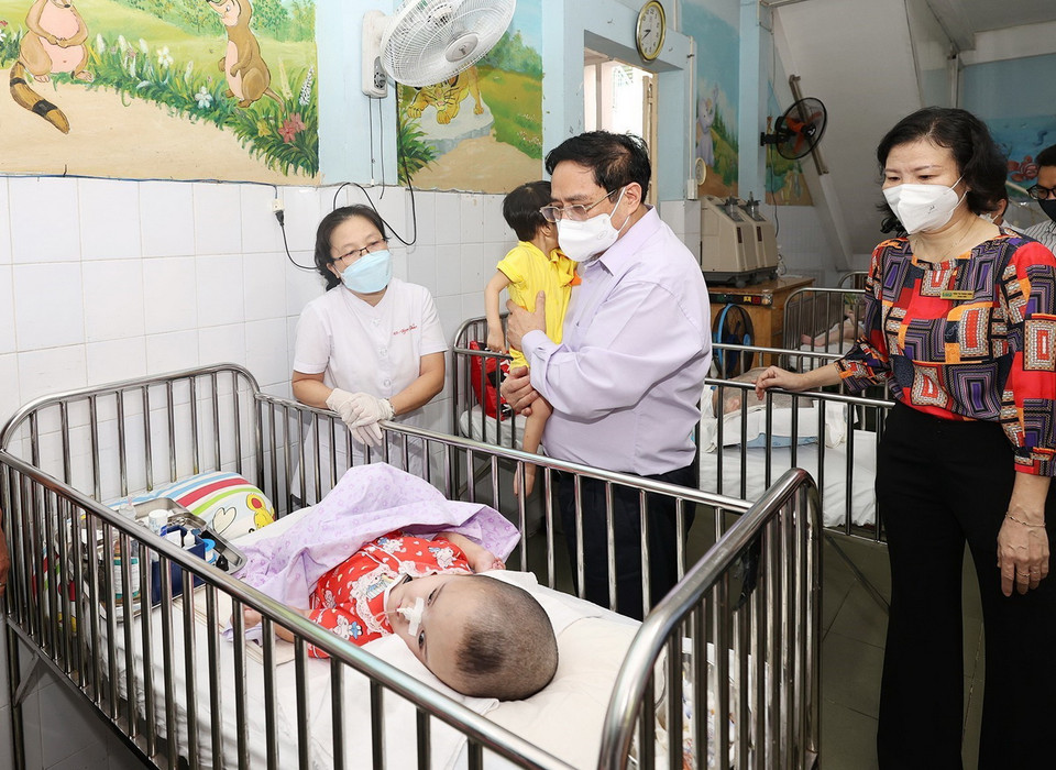 Thủ tướng Phạm Minh Chính đến tận giường thăm trẻ em đang được chăm sóc tại Trung tâm bảo trợ trẻ tàn tật mồ côi Thị Nghè. (Ảnh: Dương Giang/TTXVN)