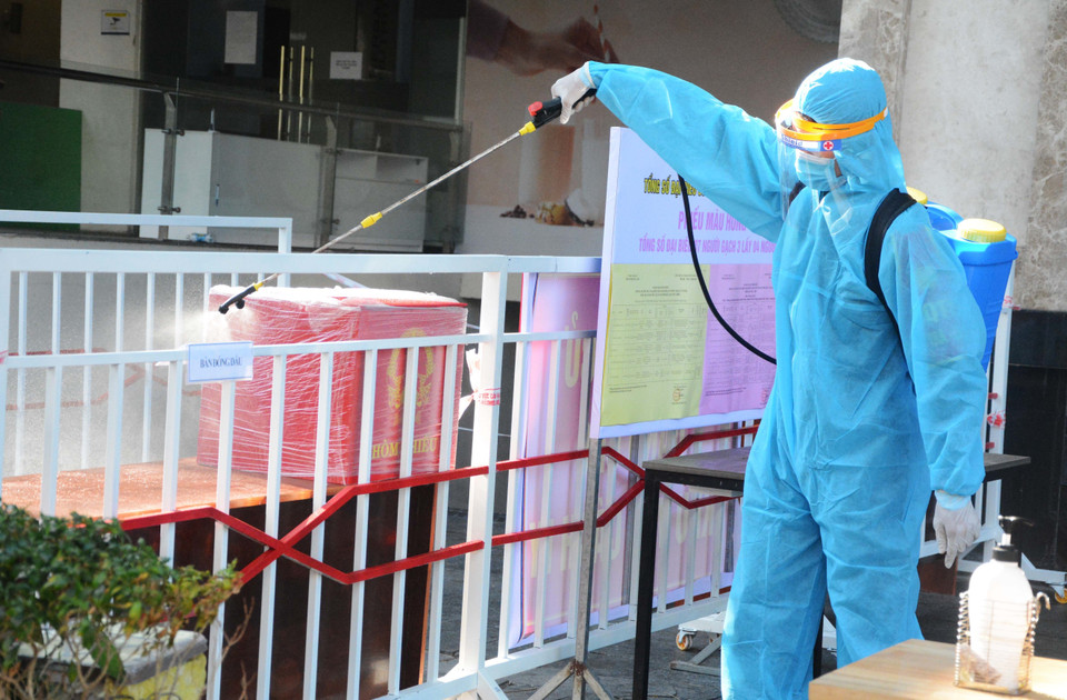 Sau khi cử tri bỏ phiếu xong, hòm phiếu nhanh chóng được xịt khử khuẩn và đưa ra xe. (Ảnh: Văn Dũng/TTXVN)