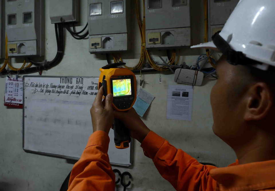 Nhân viên điện lực thuộc đoàn liên ngành của quận Bắc Từ Liêm kiểm tra, đo nhiệt độ các thiết bị phát điện tại chung cư mini 679 (số 71, ngõ 205 Xuân Đỉnh, Bắc Từ Liêm, Hà Nội). (Ảnh: Phạm Kiên/TTXVN)
