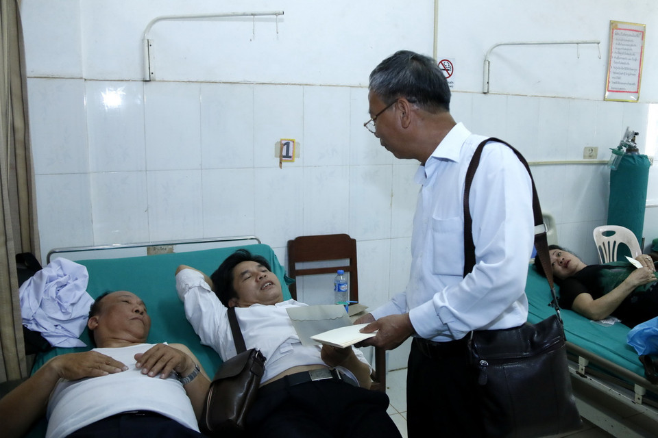 Ông Trần Công Thịnh, Tổng Lãnh sự Việt Nam tại Savannakhet, đang tặng quà và thăm hỏi các nạn nhân của vụ tai nạn. (Ảnh: Phạm Kiên/Vietnam+) 