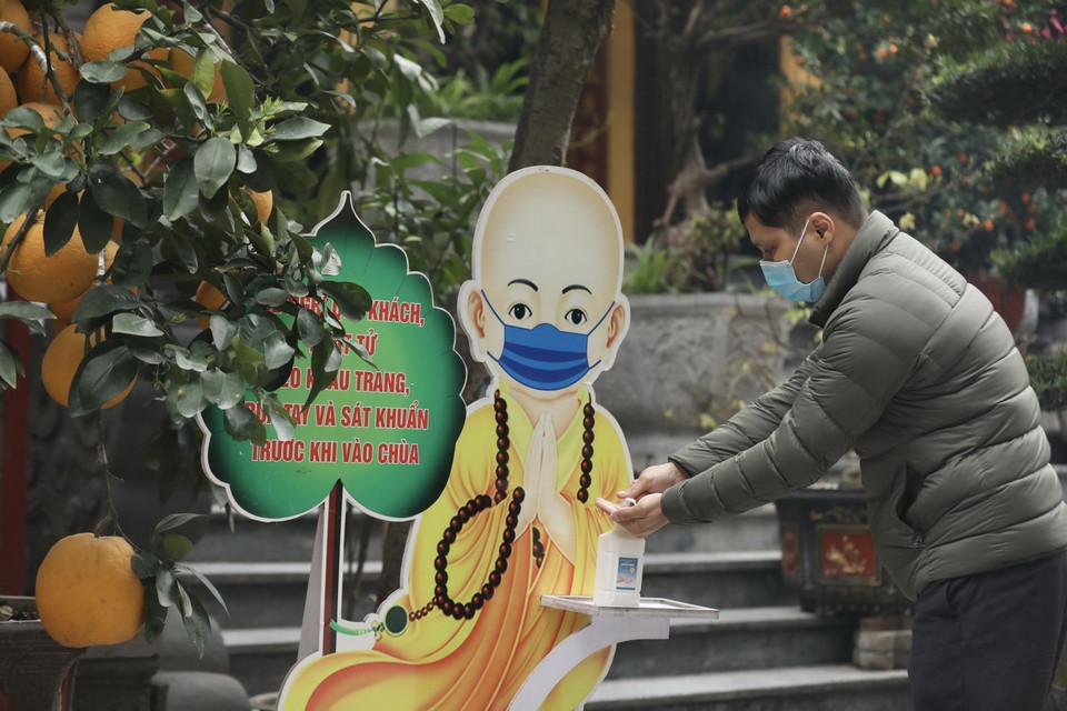 Do dịch COVID-19, người dân đến các chùa đều thực hiện quy định sát khuẩn tay. (Ảnh: Minh Quyết/TTXVN)