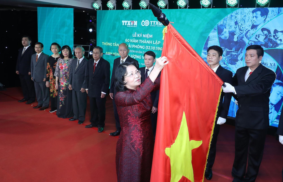Thừa ủy quyền của Chủ tịch nước, Phó Chủ tịch nước Đặng Thị Ngọc Thịnh gắn Danh hiệu Anh hùng Lực lượng vũ trang nhân dân tặng Thông tấn xã Giải phóng lên lá cờ truyền thống của TTXVN. (Ảnh: Lâm Khánh/TTXVN)