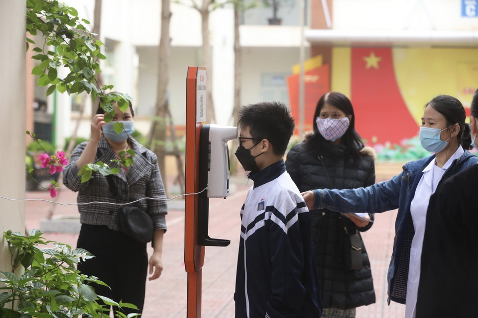  Khi đến tiêm học sinh và người nhà được hướng dẫn sát khuẩn tay và kiểm tra thân nhiệt. (Ảnh: Minh Quyết/TTXVN)