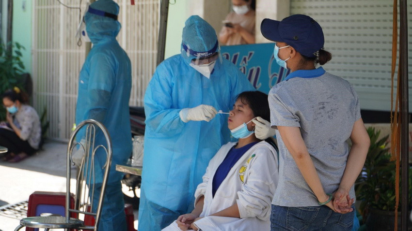 Nhân viên y tế lấy mẫu xét nghiệm cho người dân sinh sống tại khu vực hẻm bị phong tỏa. (Ảnh: TTXVN phát)