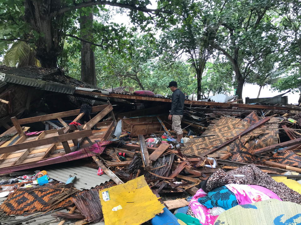 Người đàn ông thẫn thờ bên ngôi nhà tối qua còn quây quần cùng vợ con nay đã sập. (Ảnh: Đỗ Quyên/Vietnam+)