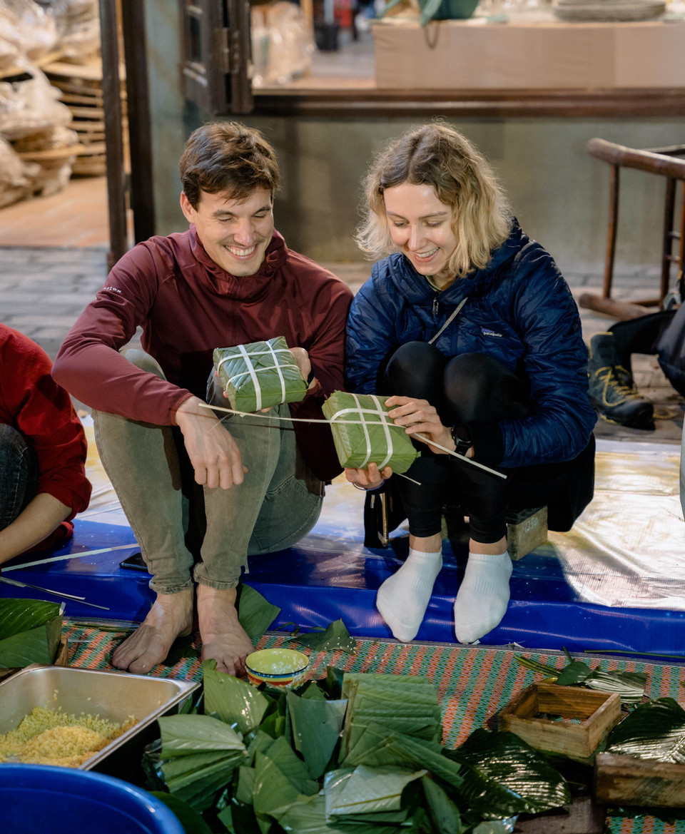 Du khách trải nghiệm gói bánh chưng. (Ảnh: Thùy Dung/TTXVN)