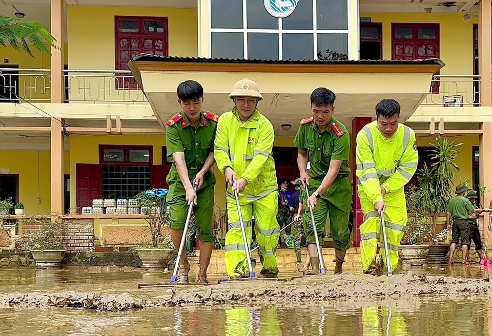 Lực lượng Công an tỉnh Quảng Bình đẩy bùn đất, tổng dọn vệ sinh tại các cơ quan công sở huyện Lệ Thủy. (Ảnh: TTXVN phát)