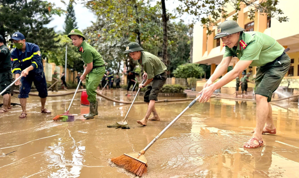 Lực lượng Công an tỉnh Quảng Bình đẩy bùn đất, tổng dọn vệ sinh tại các cơ quan công sở huyện Lệ Thủy. (Ảnh: TTXVN phát)