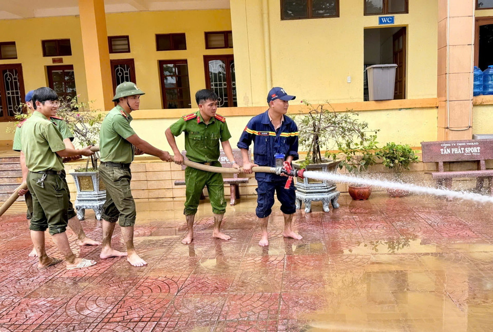 Lực lượng Công an tỉnh Quảng Bình dùng vòi xịt nước, đẩy bùn đất tại các cơ quan công sở huyện Lệ Thủy. (Ảnh: TTXVN phát)