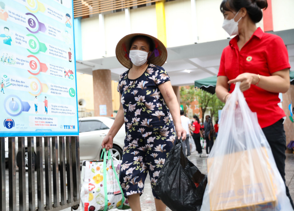 Một tình nguyện viên xách đồ giúp người dân đi Chợ nhân đạo. (Ảnh: Thanh Tùng/TTXVN)