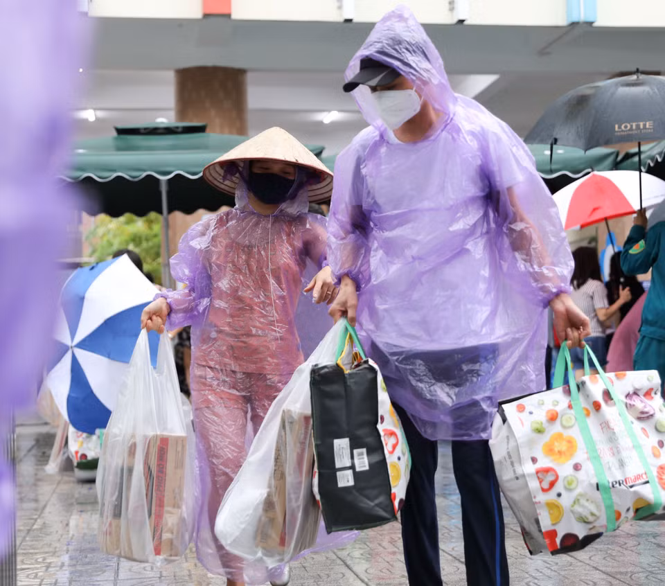 Mặc dù trời mưa to nhưng người người dân vẫn phấn khởi đến Chợ nhân đạo. (Ảnh: Thanh Tùng/TTXVN)