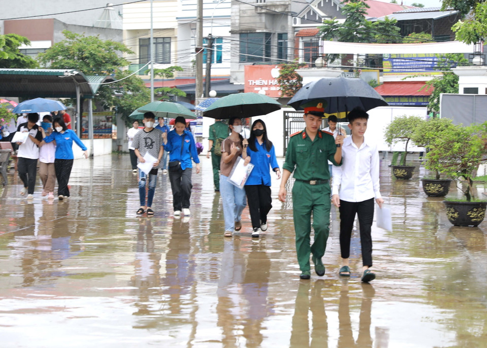 Các thí sinh được lực lượng Bộ đội và thanh niên tình nguyện che ô tại điểm thi Trường THPT Trần Hưng Đạo, huyện Tam Dương, tỉnh Vĩnh Phúc. (Ảnh: Hoàng Hùng/TTXVN)